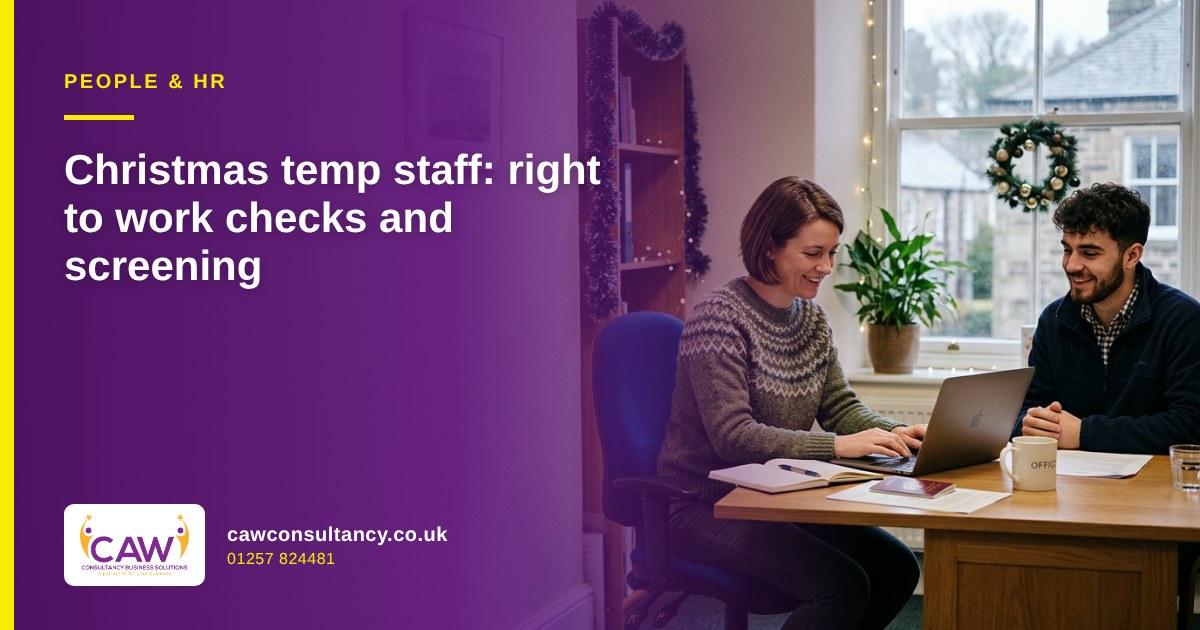 Manager checking a new starter's documents on a laptop in an office decorated for Christmas